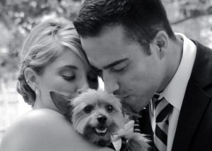 Bride and Groom holding and kissing Yorkshire Terrier outside