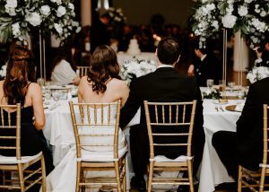 Bride and groom facing their backs to the camera sitting at their reception table
